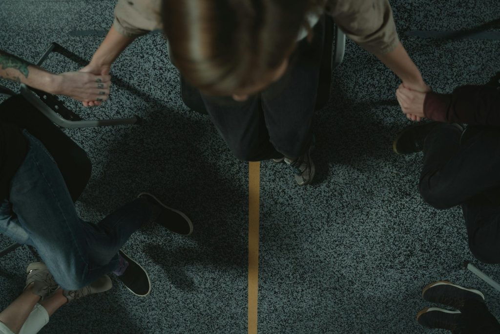 Un groupe diversifié de personnes se tenant la main en cercle, symbolisant le soutien et l'unité lors d'une séance de santé mentale.