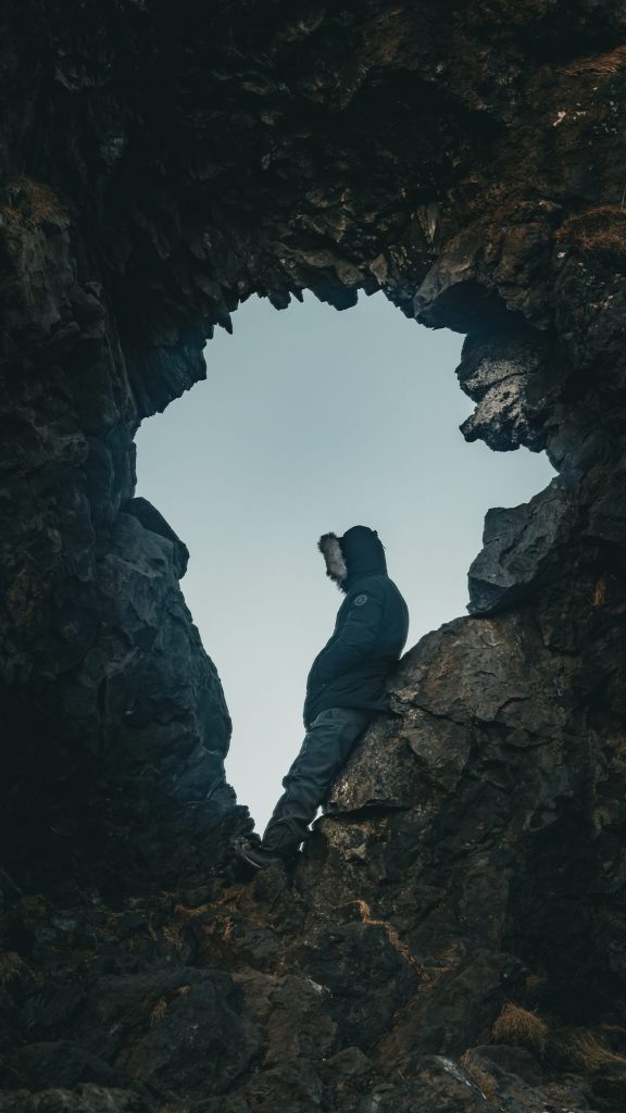 une personne debout dans une grotte regardant le ciel
